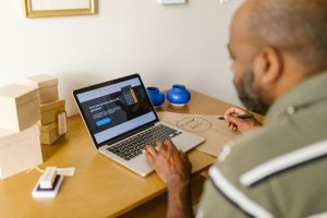 Small business owner in a UK office reviewing invoices on a laptop