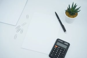 Calculator, pen, and budget spreadsheet on a desk
