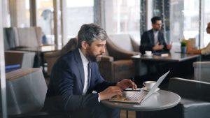 Businessman working on a laptop in a modern café setting.